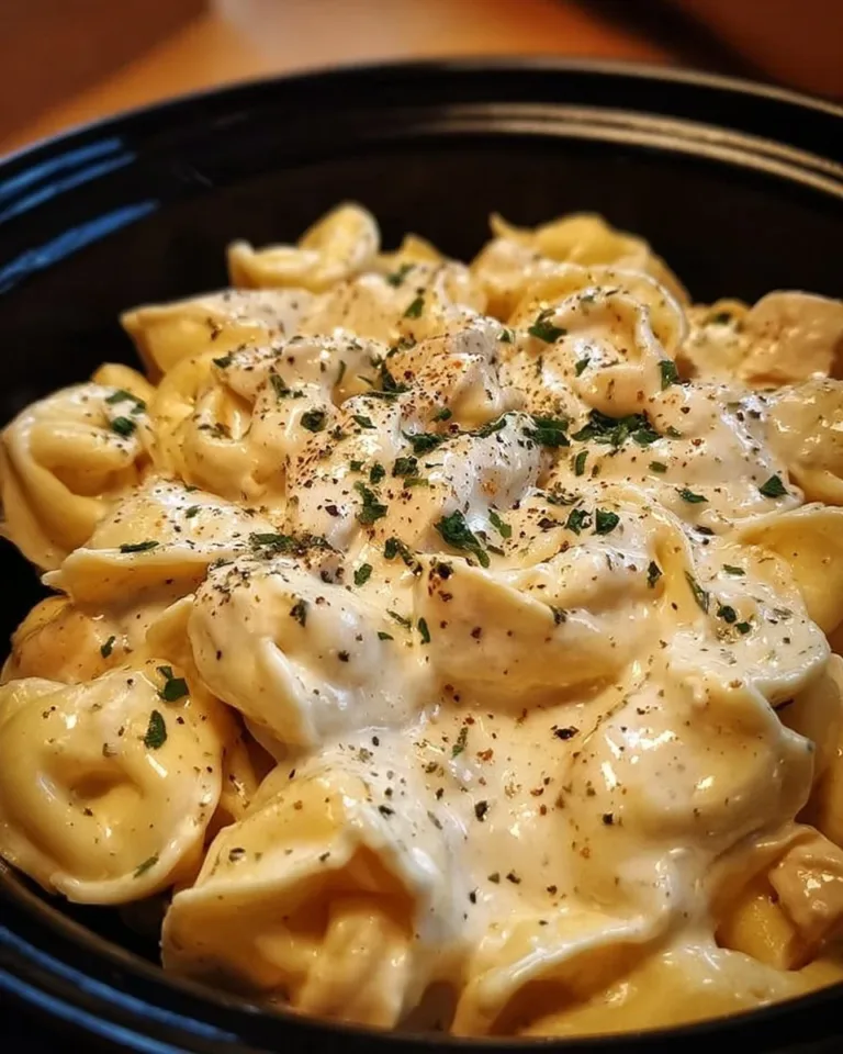 Crockpot Chicken Alfredo Tortellini in a creamy sauce with fresh herbs.